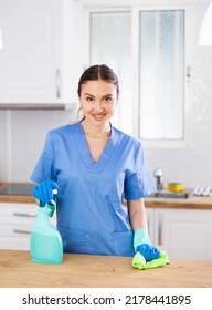 Portrait Of Confident Young Woman Professional House Cleaner Cleaning Kitchen Surfaces Using Rag And Detergent Spray