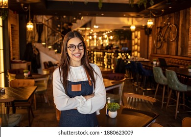 Portrait Of A Confident Young Woman Standing In The Doorway Of A Coffee Shop. Portrait Of Smiling Cafeteria Owner. Small Business Owner At Entrance Looking At Camera