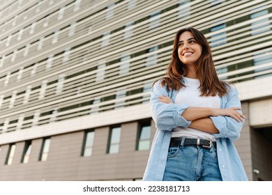 Portrait confident young woman standing in the city looking to the side with happy expression - Powered by Shutterstock