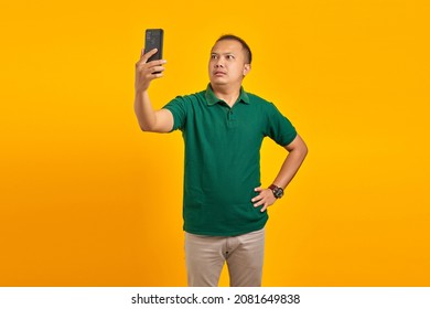 Portrait Of Confused Asian Young Man Using Mobile Phone When Not Connected To Internet Network Over Yellow Background