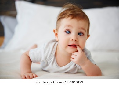 Portrait Of Confused Baby Lying On The Bed 