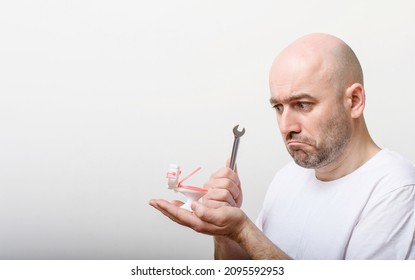 Portrait of confused bald man with toy flush toilet bowl on white background. Repair by plumber. Plumbing problems.
