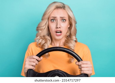 Portrait of confused scared person wear stylish t-shirt hold steering wheel astonished staring isolated on turquoise color background