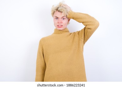 Portrait of confused Young handsome Caucasian blond man standing against white background holding hand on hair and frowning, panicking, losing memory. Worried and anxious can not remember anything. - Powered by Shutterstock