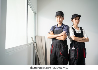 Portrait of Construction worker smile and look at camera after work. Asian Craftsman builder or Carpenter man and woman wear blue cap with confident face and cross arm after repair and renovate house. - Powered by Shutterstock