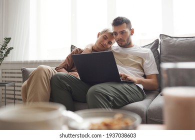 Portrait Of Contemporary Gay Couple In Everyday Life, Two Young Men Using Laptop Together While Relaxing On Couch At Home, Copy Space