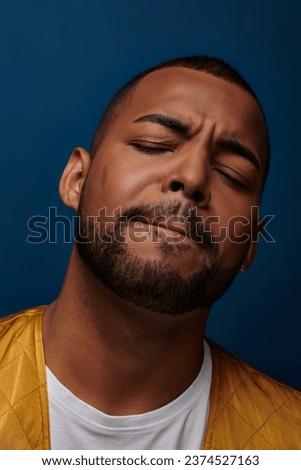 portrait of contented handsome african american man with beard closing his eyes, fashion concept