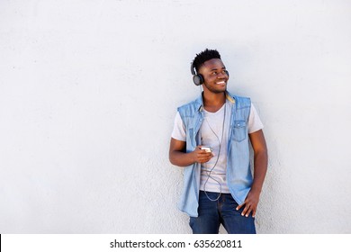 Portrait Of Cool African Guy With Mobile Phone And Headphones Listening To Music