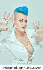 Portrait of a cool girl punk rock musician with bright makeup and blue mohawk posing at studio expressively. Youth alternative culture. White background.