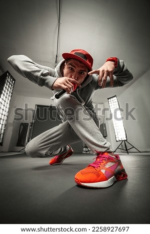 Portrait of cool looking hiphopper singing in sportswear. Wide angle lens effect.
