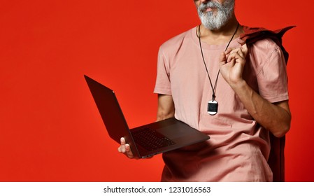 Portrait Of Cool, Manly, Fashionable Old Man Senior Male With Thick Gray Beard Using Laptop Computer, Standing At Full Height And Looking At The Picture In The Studio