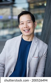 Portrait Of A Cool Middle Aged Asian Man Smiling Outdoors