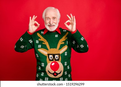 Portrait Of Cool Positive Old Man Show Okay Sign  Recommend Winter Season Tradition Discounts Wear Trend Pullover With Reindeer Pattern Decor Isolated Over Red Color Background