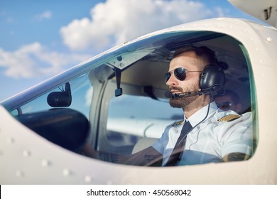 Portrait Of Cool Young Adult Pilot Sitting In Private Air Plane Ready To Take Off. Bright Summer Day, Handsome Male Model