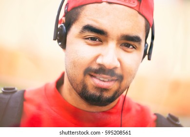 Portrait Of Cool Young Black Boy Listening To Rap Music In Headphones Outdoor.Hip Hop Guy Enjoy Listening To Music Outside.Handsome Male African Model Posing With Friendly Smile.Student Age Boy