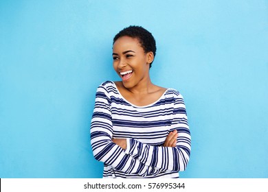 Portrait of cool young black woman laughing against blue wall