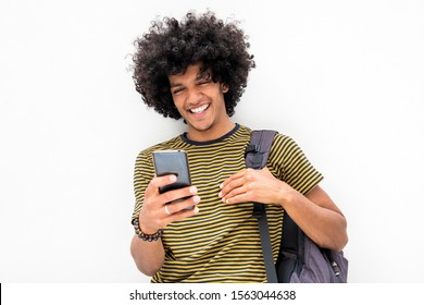 Portrait Of Cool Young Guy With Bag Looking At Cellphone And Smiling