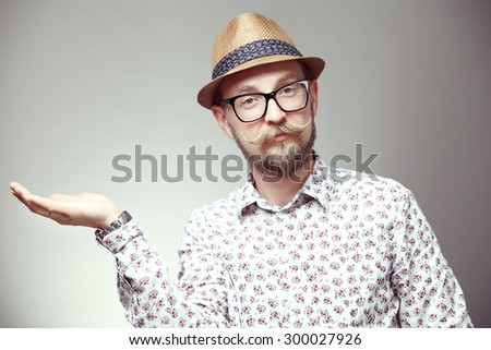 Portrait of cool young hipster in a hat holding his arm,  isolated on grey background
