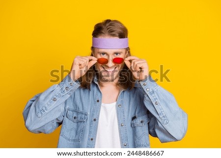 Portrait of cool young man touch sunglass wear denim shirt isolated on yellow color background