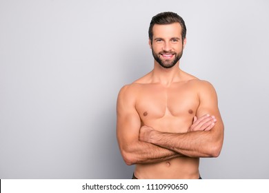 Portrait with copy space of attractive, virile, harsh, sporty, manly, stunning man with crossed arms, muscular, naked torso, looking at camera, isolated on gray background