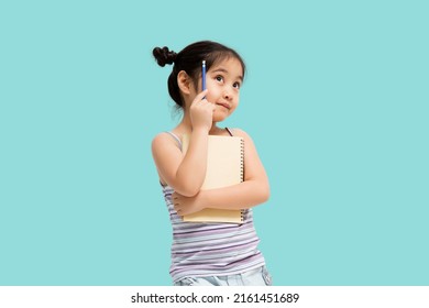 Portrait With Copy Space Empty Place Of Thoughtful Little Asian Girl Having Paper And Pencil In Hands Looking Up, Writer Waiting For Muse, Isolated On Green Background