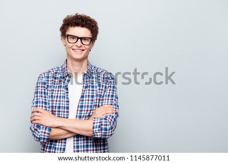 Portrait with copy space and empty place for text with young man in glasses with crossed arms looking at camera isolated on light grey background
