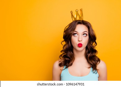 Portrait with copyspace empty place of funny stupid girl looking at crown on head with eyes sending kiss with pout lips isolated on yellow background advertisement concept