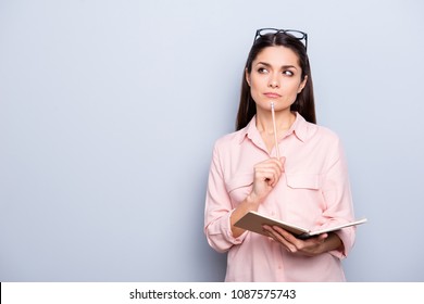 Portrait with copyspace of thoughtful concentrated busy charming woman having notepad and pen in hands planning, expertising, analyzing isolated on grey background, advertisement concept - Powered by Shutterstock