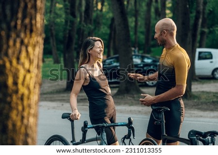 Portrait of a couple of athletes dressed in activewear standing and talking while preparing for a race or an outdoor activity. Professional bicycle racers in action. Concept of endurance and strength