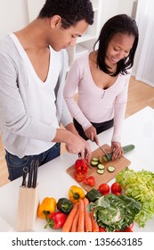 Portrait Of Couple Chopping Vegetables In Kitchen