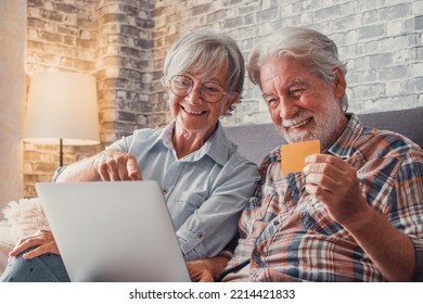 Portrait Of Couple Of Cute Two Happy And Excited Seniors Buying And Spending Money Shopping Online With Laptop On The Sofa At Home. Using Credit Card Together Buying On Internet.