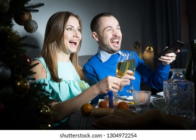 Portrait Of Couple In Festive Mood During Celebration Of Christmas Watching Tv In Dark Room