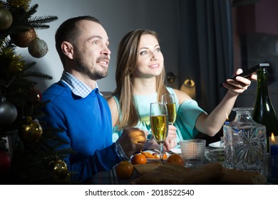 Portrait Of Couple In Festive Mood During Celebration Of Christmas Watching Tv In Dark Room