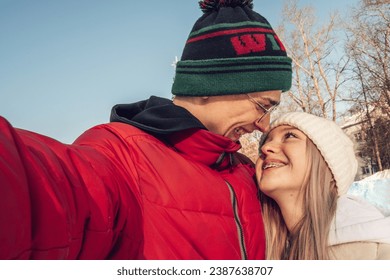 Portrait of a couple of happy teenagers taking photo of yourself, selfie,on a winter day at an outdoor skating rink.Winter entertainment,leisure activity,Valentine's day,generation Z. - Powered by Shutterstock