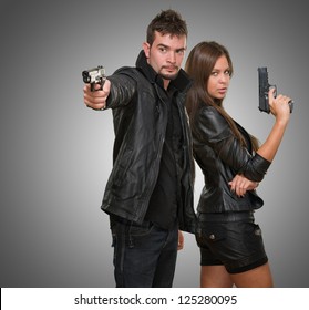 Portrait of a couple holding guns against a grey background