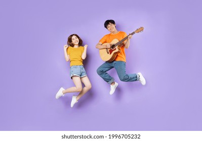 Portrait of a couple jumping up, isolated on purple background