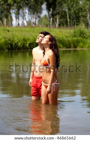 Portrait of couple looking at sun together and standing in the lake