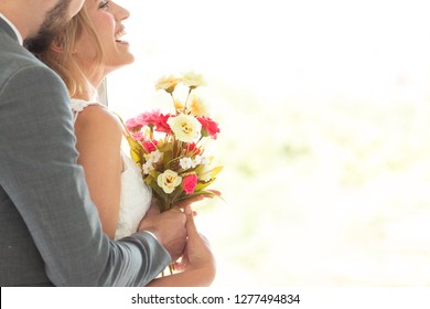 A portrait of couple love or bride in wedding studio while try to fitting suit and dress with bouquet flowers as romantic people concept