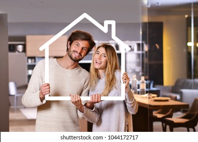 Portrait of a couple in love who have just bought a house and is moving. The bride and groom smile and hold and hold the outline of a house the in their hands. Concept of: home, family, ecology