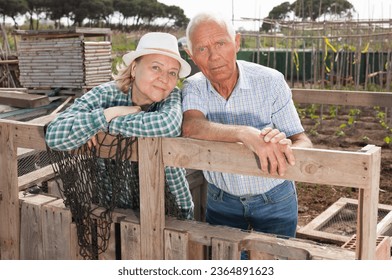 Portrait of couple of mature man and woman gardeners near wooden fence in garden outdoor - Shutterstock ID 2364891623