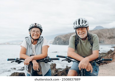 Portrait of couple of old and happy in love seniors looking at the camera smiling and having fun with their bikes in the nature outdoors together feeling good and healthy. - Powered by Shutterstock