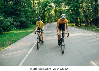 Portrait of a couple of riders cycling on racing bikes on the highway. Active lifestyle and sport concept. Sporty couple of cyclist riding a bicycle on the road in the woods. Copy space. - Powered by Shutterstock