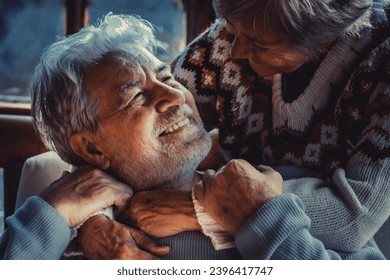 Portrait of couple of senior people in love at home in the evening dark light. Old man smile at her mature woman wife hugging and enjoying relationship. Winter home background. Elderly people life - Shutterstock ID 2396417747