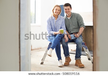 Portrait Of Couple Sitting In Property Being Rennovated