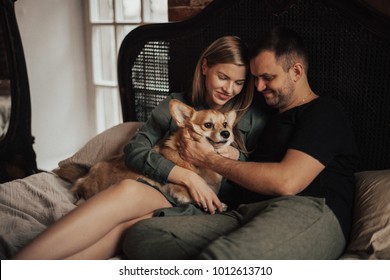 Portrait of couple with small pet. A man is hugging a woman. Couple in love at home. A man and a woman are talking and laughing. The concept of a happy family. - Powered by Shutterstock