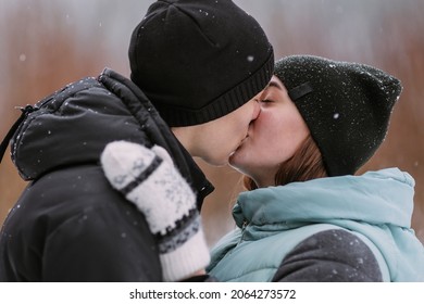 Portrait Of Couple Of Teenagers Kissing In Winter Forest