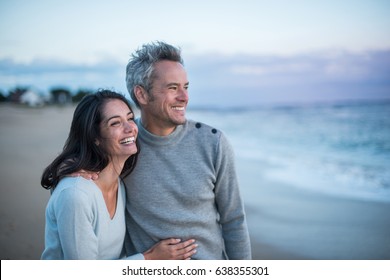 Portrait of a  couple walking on the beach, they are wearing sweaters and the man has gray hair - Powered by Shutterstock