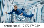 Portrait of a Courageous Caucasian Female Astronaut on Board a Spacecraft, Floating in Zero Gravity and Smiling At The Camera, Waving. Space Travel, Solar System Exploration and Colonization Concept