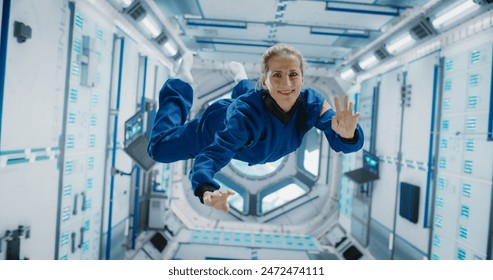 Portrait of a Courageous Caucasian Female Astronaut on Board a Spacecraft, Floating in Zero Gravity and Smiling At The Camera, Waving. Deep Space Travel, Solar System Exploration and Colonization. - Powered by Shutterstock