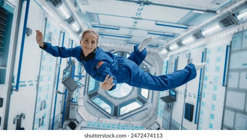 Portrait of a Courageous Caucasian Female Astronaut on Board a Spacecraft, Floating in Zero Gravity and Smiling At The Camera, Waving. Space Travel, Solar System Exploration and Colonization. - Powered by Shutterstock
